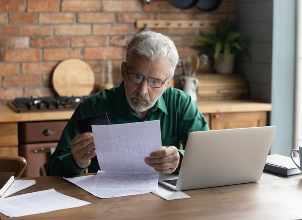 Concerned looking older man looking at paper document.